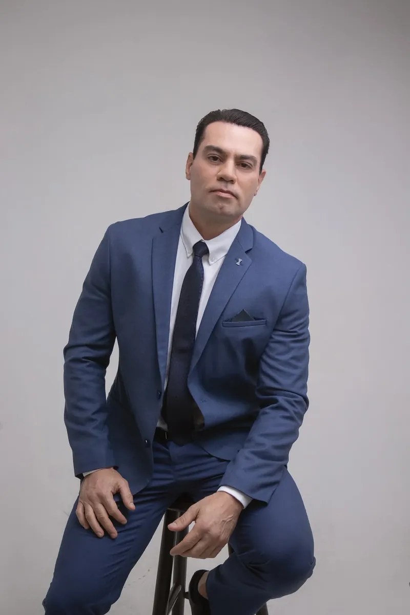 Dr. Diego Fernandez Pollito, de terno azul, apoiado em um banco alto.